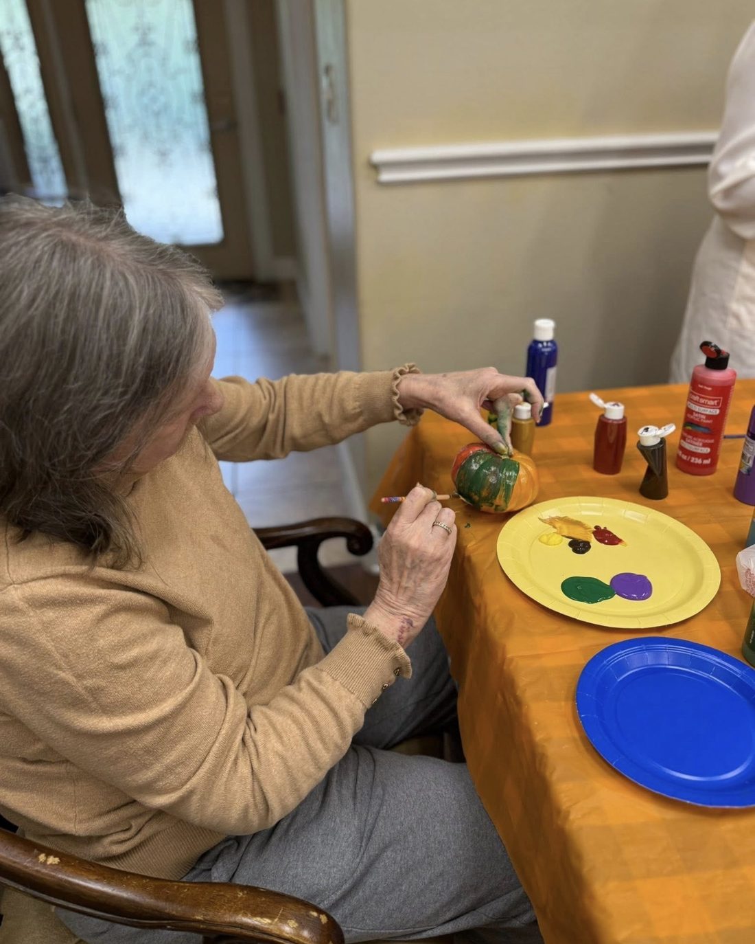 Resident painting a pumpkin for fall